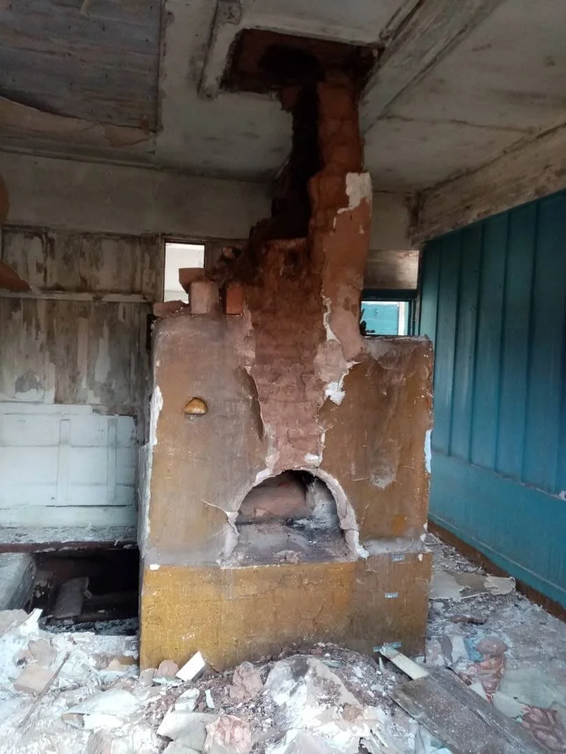 The stove in a photograph accompanying the house’s history. It records a stage in the restoration archive rather than the present appearance of the museum interior.