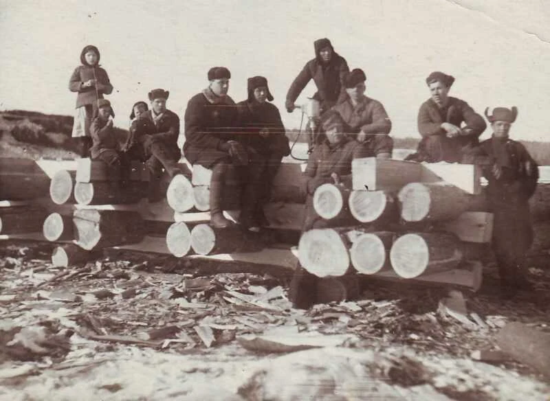 Group photograph beside timber construction in the account of old Tangui and relocation. Participants and the exact shooting date are not supplied. It is not presented as a precisely dated record of dismantling or moving a specific house.